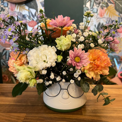 Smiling Planter - A cheerful floral arrangement presented in a decorative ceramic planter, filled with fresh seasonal flowers and foliage. Flowers are dependent on seasonal availability.