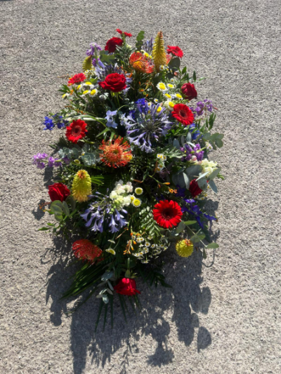 Vibrant Tribute Spray - A striking funeral spray featuring a colourful mix of seasonal flowers, thoughtfully handcrafted as a heartfelt farewell. Flowers are dependent on seasonal availability.